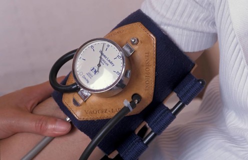 A close-up of a blood pressure monitor on a person's arm with a leather gauge attachment