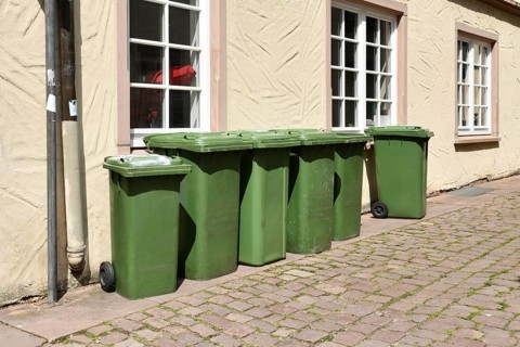 Green wheelie bins placed on residential street in Germany for waste collection
