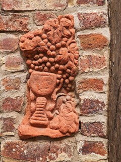 Clay work in house wall, pottery, handicraft, art, grapes, wine glass, red clinker, wooden beams,