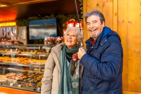 Cheerful senior couple enjoying christmas market, shopping and having fun during winter holidays