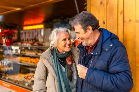 Happy senior couple smiling and enjoying time together during christmas holidays at a winter market