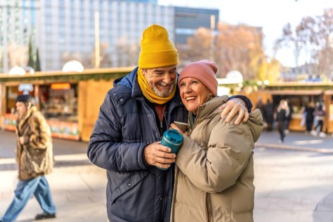 Elderly couple sharing warm drinks while enjoying the festive atmosphere of an outdoor christmas