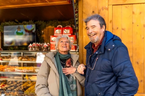 Cheerful senior couple smiling and enjoying the festive atmosphere at a christmas market in a