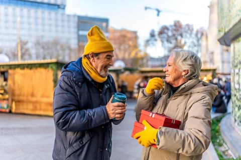 Elderly couple exchanging christmas presents and enjoying a hot beverage at a traditional christmas