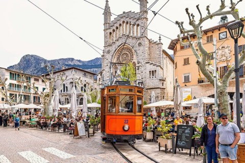 Old vintage train on the city square outside the church between outdoor restaurants and tourists,