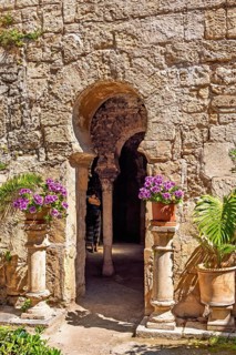 Flowers on pedestals at an opening into the Arab baths old building with oriental architecture,