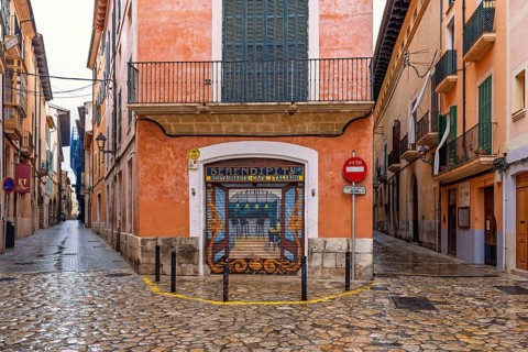 Empty street in a residential area with a painting on a shutter at a cafe on a street corner, Palma