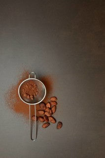 Kitchen sieve with cocoa powder, cocoa and cocoa beans