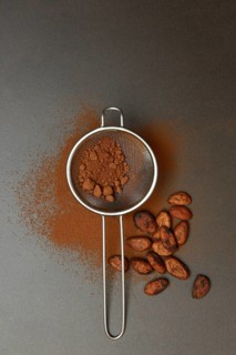 Kitchen sieve with cocoa powder, cocoa and cocoa beans