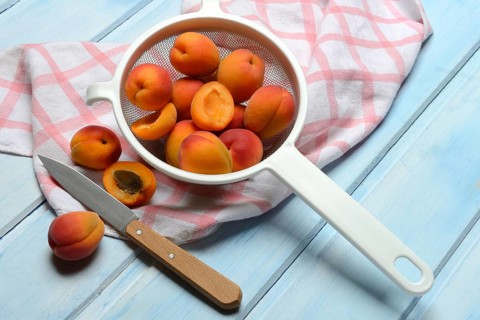 Apricots in colander, halved, Prunus armeniaca