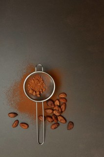 Kitchen sieve with cocoa powder, cocoa and cocoa beans
