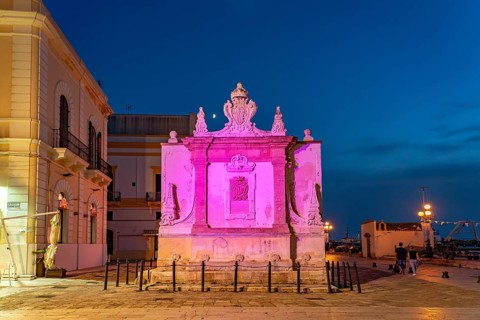 The colourfully illuminated Greek fountain Fontana Greca at dusk, Gallipoli, Apulia, Italy