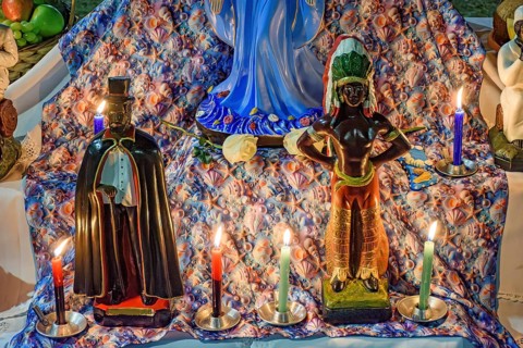 Umbanda altar with its deities and objects of worship lit by candles at night, Belo Horizonte,