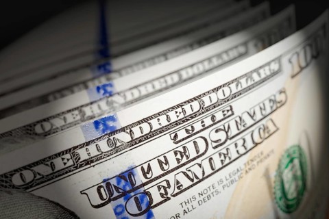 Spot lit abstract close-up angle of U.S. 100 dollar bills isolated on a black background