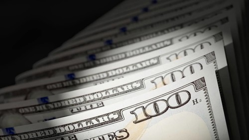 Spot lit abstract close-up angle of U.S. 100 dollar bills isolated on a black background
