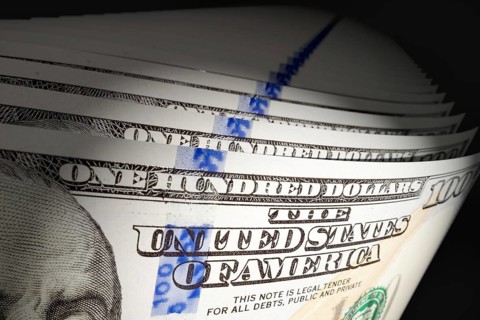 Spot lit abstract close-up angle of U.S. 100 dollar bills isolated on a black background
