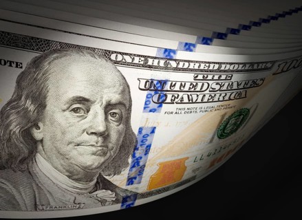 Spot lit abstract close-up angle of U.S. 100 dollar bills isolated on a black background