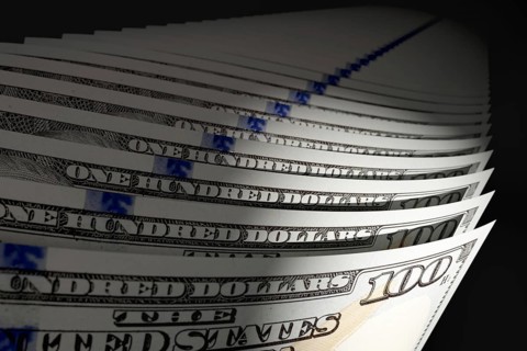 Spot lit abstract close-up angle of U.S. 100 dollar bills isolated on a black background