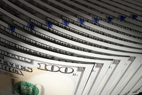 Spot lit abstract close-up angle of U.S. 100 dollar bills isolated on a black background