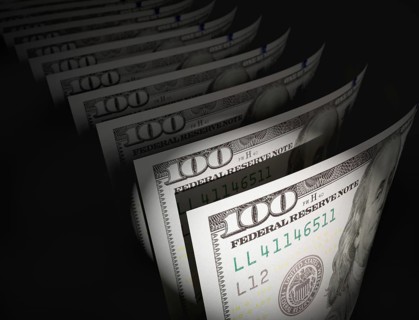 Spot lit abstract close-up angle of U.S. 100 dollar bills isolated on a black background