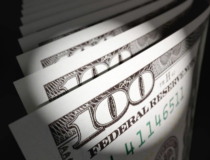 Spot lit abstract close-up angle of U.S. 100 dollar bills isolated on a black background
