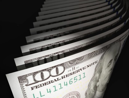 Spot lit abstract close-up angle of U.S. 100 dollar bills isolated on a black background