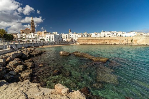 City view of Monopoli with the cathedral, city wall and the beach Cala Porta Vecchia, Apulia, Italy