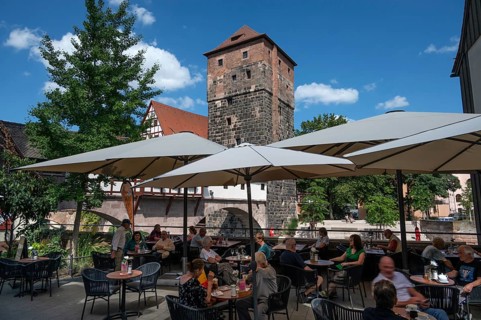 Historic water tower built around 1325, in front a café on the Pegnitz, Nuremberg, Middle