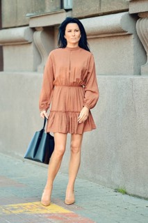 A woman walks confidently along a busy sidewalk, wearing a fashionable dress and carrying a tote