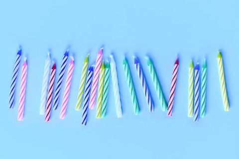 Row of colorful birthday candles on blue background