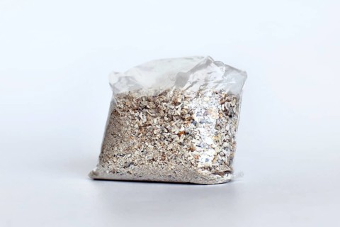 Small plastic bag containing ash of a pet cat after cremation on white background