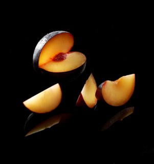 Plum, plum slices against a black background