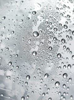 Drops of water on plastic bottle, neutrally illuminated, detailed view