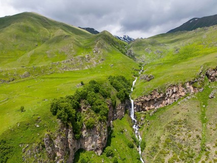 Landscape with long waterfall between green mountains under a cloudy sky, aerial view, Toti