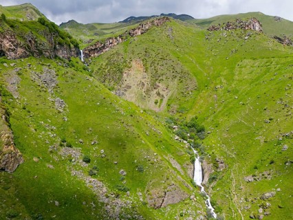 Waterfall in a green valley between rocky mountains, aerial view, Toti waterfall or Arsha