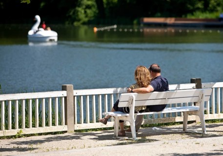 Couple sitting on a wooden bench and looking at the spa pond in the spa gardens, Großer Teich, Bad