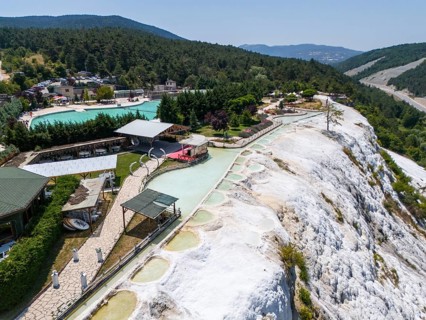 Thermal springs and buildings in a green landscape with limestone formations, aerial view, Akkaya