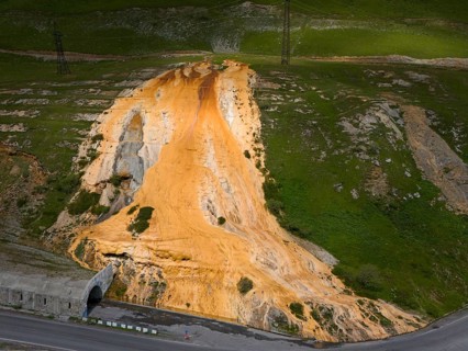 A hill with a distinctive orange rock formation next to a road with a bridge, aerial view, Bidara