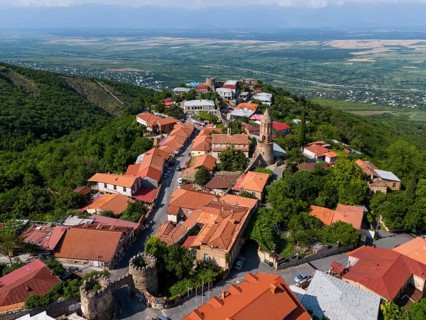 Surrounded by hills lies a picturesque village with tiled roofs and a church overlooking the