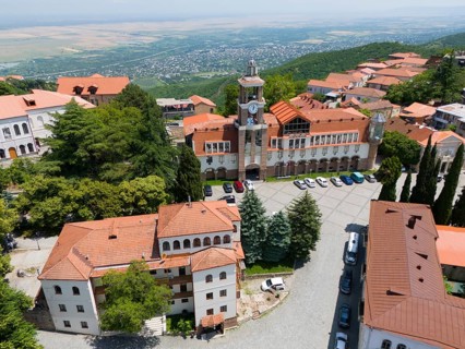 Square with a dominant tower and traditional buildings surrounded by green hills, aerial view,