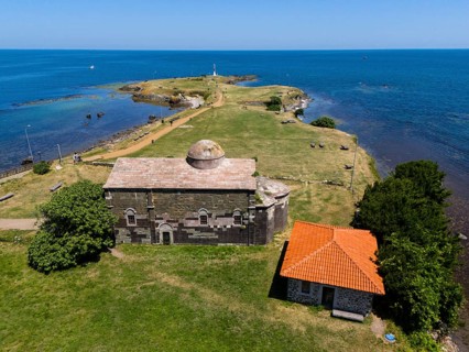 Aerial view of a historic church on the coast with neighbouring building and wide sea horizon,