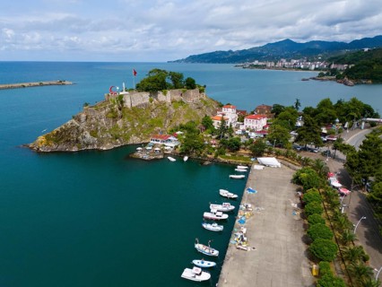 Harbour view with small boats, castle and coastal road next to mountains, aerial view, fortress,