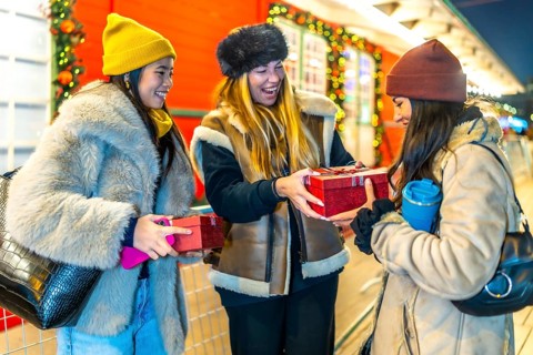 Three joyful women exchanging christmas gifts while enjoying the festive atmosphere of a