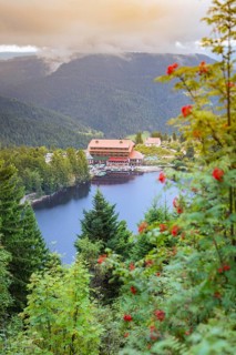 Picturesque view of a house on the lake surrounded by wooded mountains at dusk, Mummelsee, Seebach,