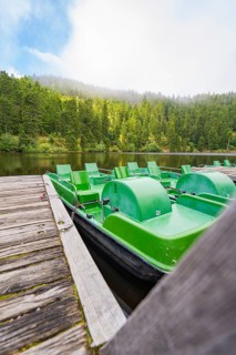 Green pedal boats on a jetty, with a forest and lake in the background, Mummelsee, Seebach, Ortenau