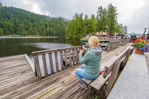 Woman at the lake photographed with her smartphone from a wooden jetty, Mummelsee, Seebach, Ortenau