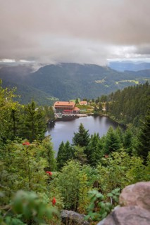 View over a lake with mountains and houses under a cloudy sky, Mummelsee, Seebach, Ortenau