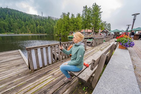 Woman on a wooden footbridge next to a lake with a camera in her hand, Mummelsee, Seebach, Ortenau