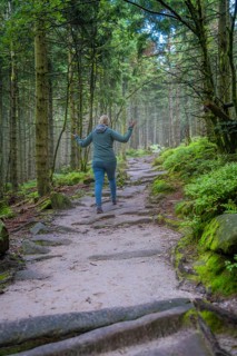 Woman walking along a forest path, surrounded by trees and moss, joyful movement, Mummelsee,