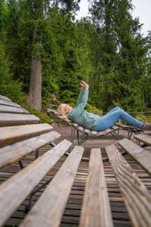 Woman lying relaxed on a wooden bench in a wooded area, Mummelsee, Seebach, Ortenau district, Black